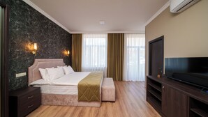 A modern hotel room with a large bed, a TV, and a wooden floor.