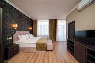 Una habitación de hotel moderna con una cama grande, televisión y suelo de madera.