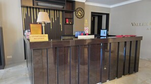 A reception desk with a sign reading "Vallex A.I. Reception," a clock, and a digital screen. - Vallex Garden Hotel Alaverdi (Alaverdi)
