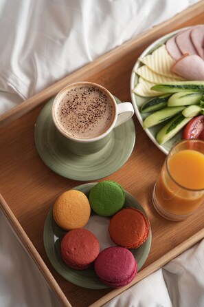 A tray with a cup of coffee, a glass of orange juice, and a plate of colorful macarons and sliced fruits. - Vallex Garden Hotel Alaverdi (Alaverdi)