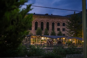 A building with arched windows and a covered outdoor seating area with tables and chairs. - Vallex Garden Hotel Alaverdi (Alaverdi)