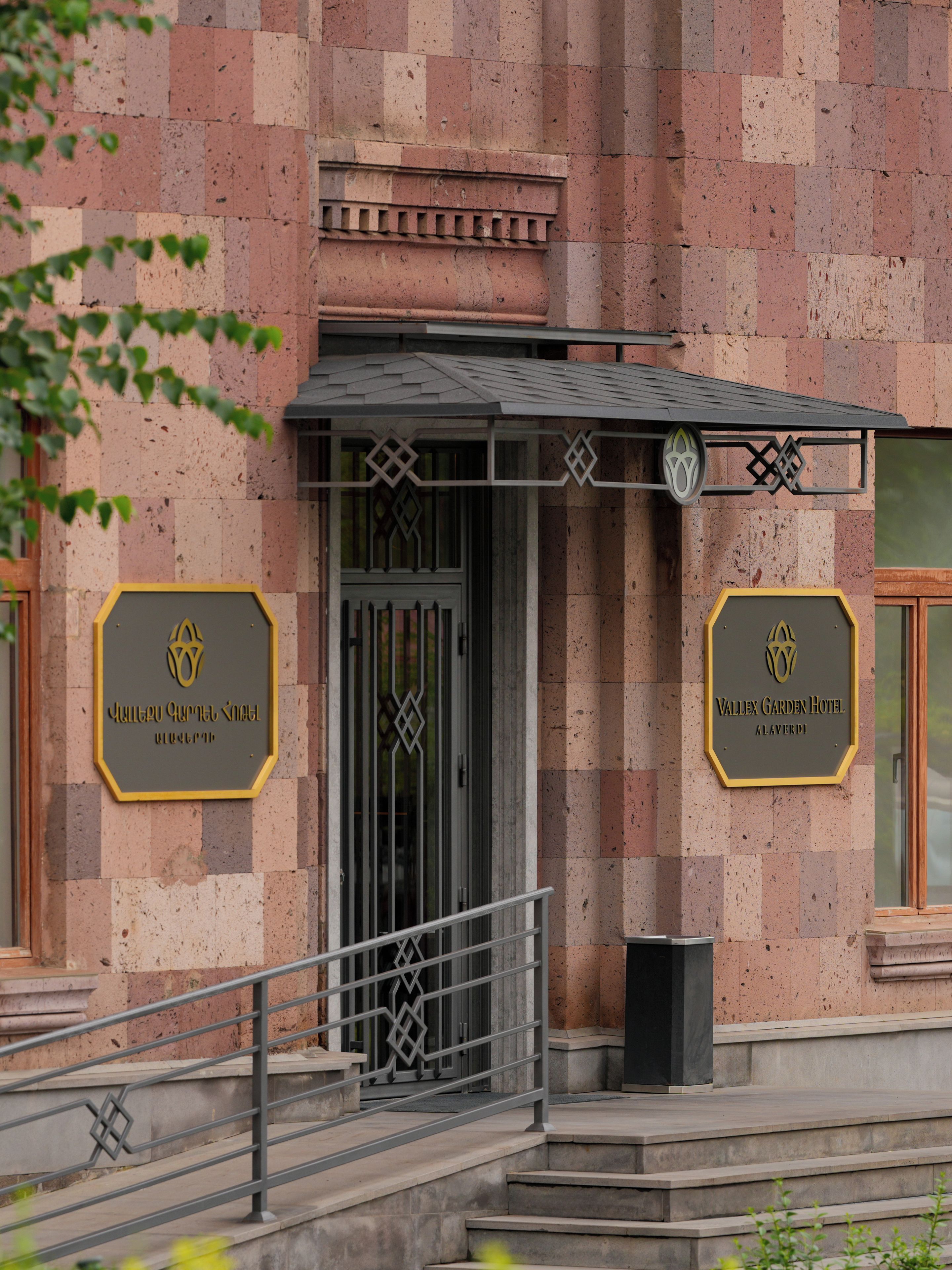A hotel entrance with a checkered facade, a gated entrance, and two signs indicating the hotel's name.
