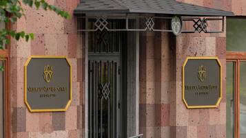 A hotel entrance with a checkered facade, a gated entrance, and two signs indicating the hotel's name.