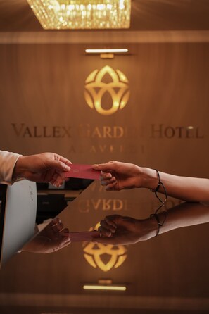 A hand holding a red card, possibly for hotel check-in, with a logo and the name 'Vallex Gard Hotel' visible in the background. - Vallex Garden Hotel Alaverdi (Alaverdi)