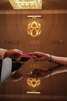Una mano sosteniendo una tarjeta roja, posiblemente para el registro de un hotel, con un logotipo y el nombre 'Vallex Gard Hotel' visible al fondo.
