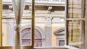 Blick durch ein Fenster mit architektonischen Details wie Rundbogenöffnungen und dekorativen Stuckleisten.