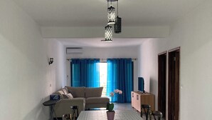 Ein geräumiges Wohnzimmer mit Esstisch, Sofa und einer Topfpflanze.