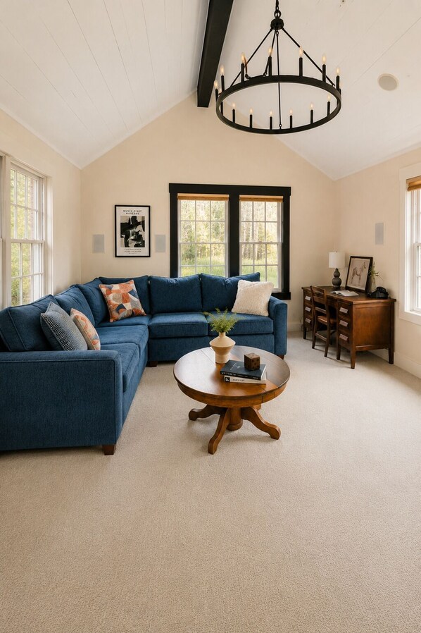 A living room with a sectional sofa, a round coffee table, and a chandelier.