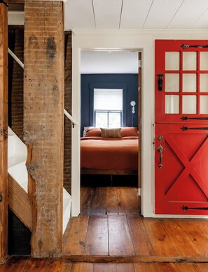 Una camera da letto con un letto, una porta rossa e una scala in legno.