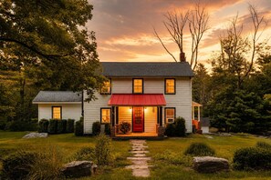 Una casa a due piani con un tenda rossa e un vialetto in pietra che conduce all'ingresso.