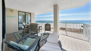 Ein Balkon mit Blick auf den Strand, ausgestattet mit Liegestühlen und einem Tisch.