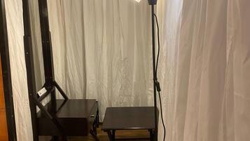 A room with a wooden floor, a table, a chair, and a floor lamp.