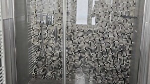 A modern bathroom with a glass-enclosed shower, tiled walls, and a large mirror. - PRIMAFILA PREMIUM GUEST HOUSE  (Sanremo)