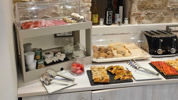A breakfast buffet with various food items, a toaster, and condiments. - PRIMAFILA PREMIUM GUEST HOUSE  (Sanremo)