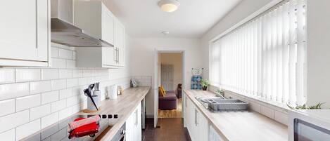 A modern kitchen with white cabinetry, a built-in oven, a microwave, and a sink.