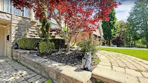 A stone pathway leading to a house with a well-maintained garden, including a hedge and a bird sculpture. - Custom Built Home in Richmond Hill (Richmond Hill)