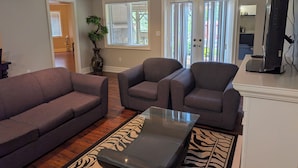 A living room with a sofa, armchairs, a glass coffee table, a zebra-patterned rug, and a television. - Custom Built Home in Richmond Hill (Richmond Hill)