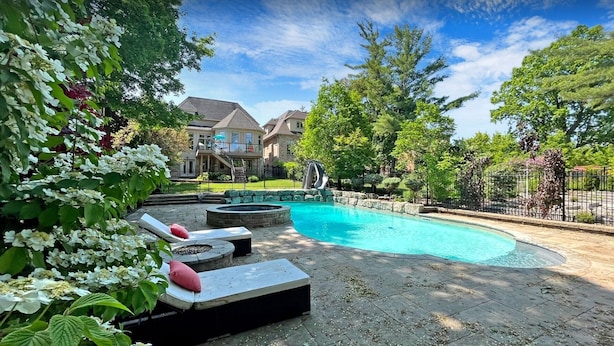 A swimming pool with lounge chairs, a fire pit, and a slide. - Custom Built Home in Richmond Hill (Richmond Hill)