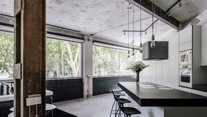 Une cuisine moderne avec un coin bar, de grandes fenêtres et une vue sur les arbres.