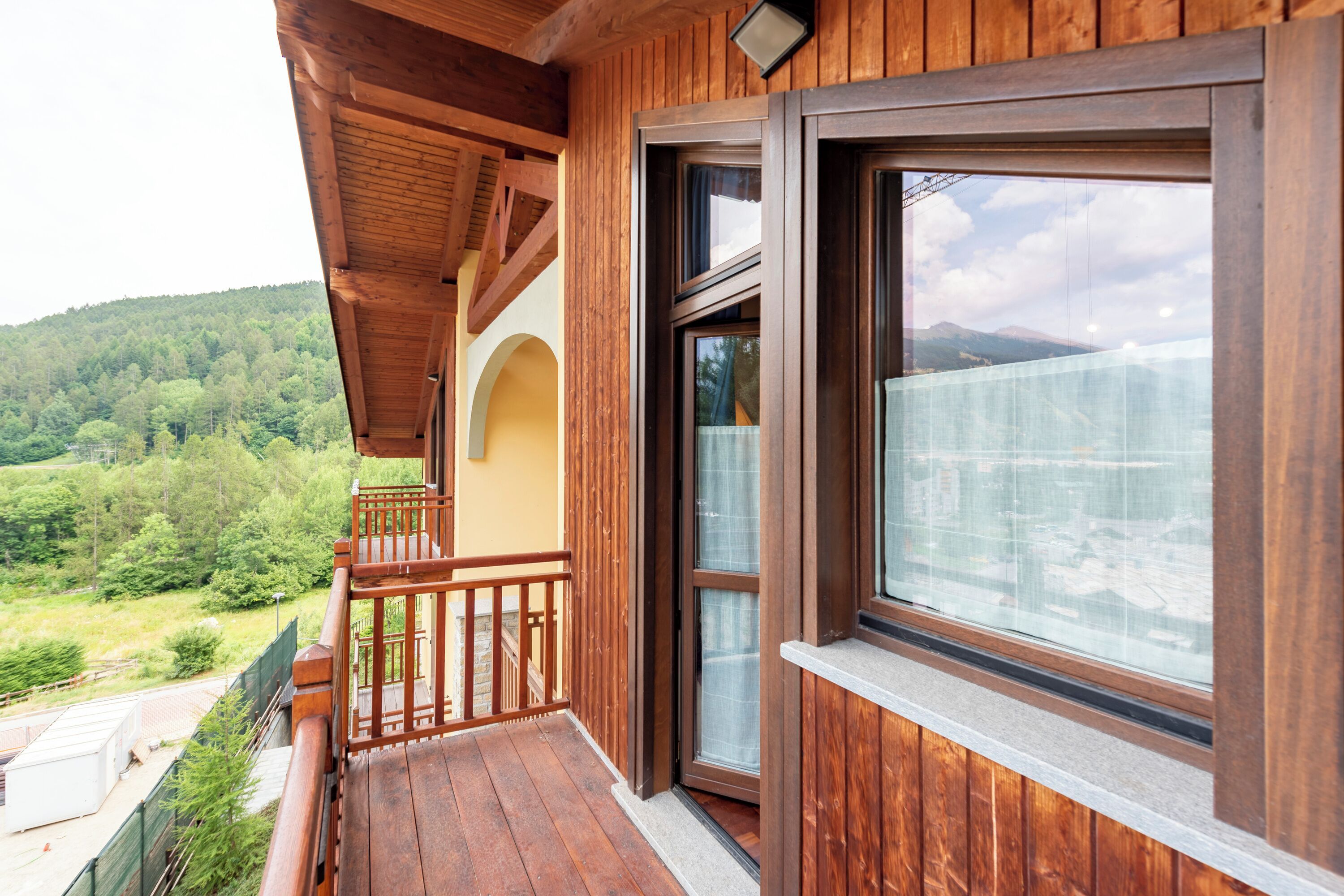 A wooden balcony with a view of a forested area.