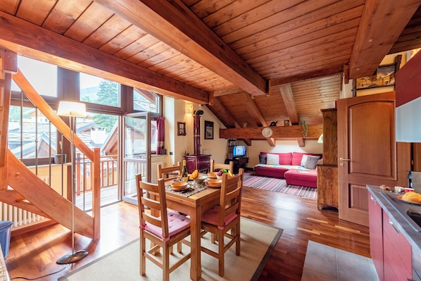 Un interior de madera con una mesa de comedor, sillas, un sofá y una zona de cocina.