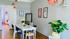 Un comedor con una mesa y sillas blancas, una lámpara colgante y una estatua de Buda en un estante.
