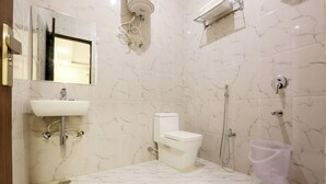 A bathroom with a toilet, sink, and shower. - Hotel Devrana (New Delhi)