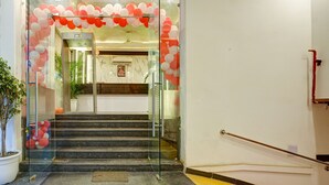 A staircase with glass railings leading to an interior space decorated with red and white balloons. - Hotel Devrana (New Delhi)