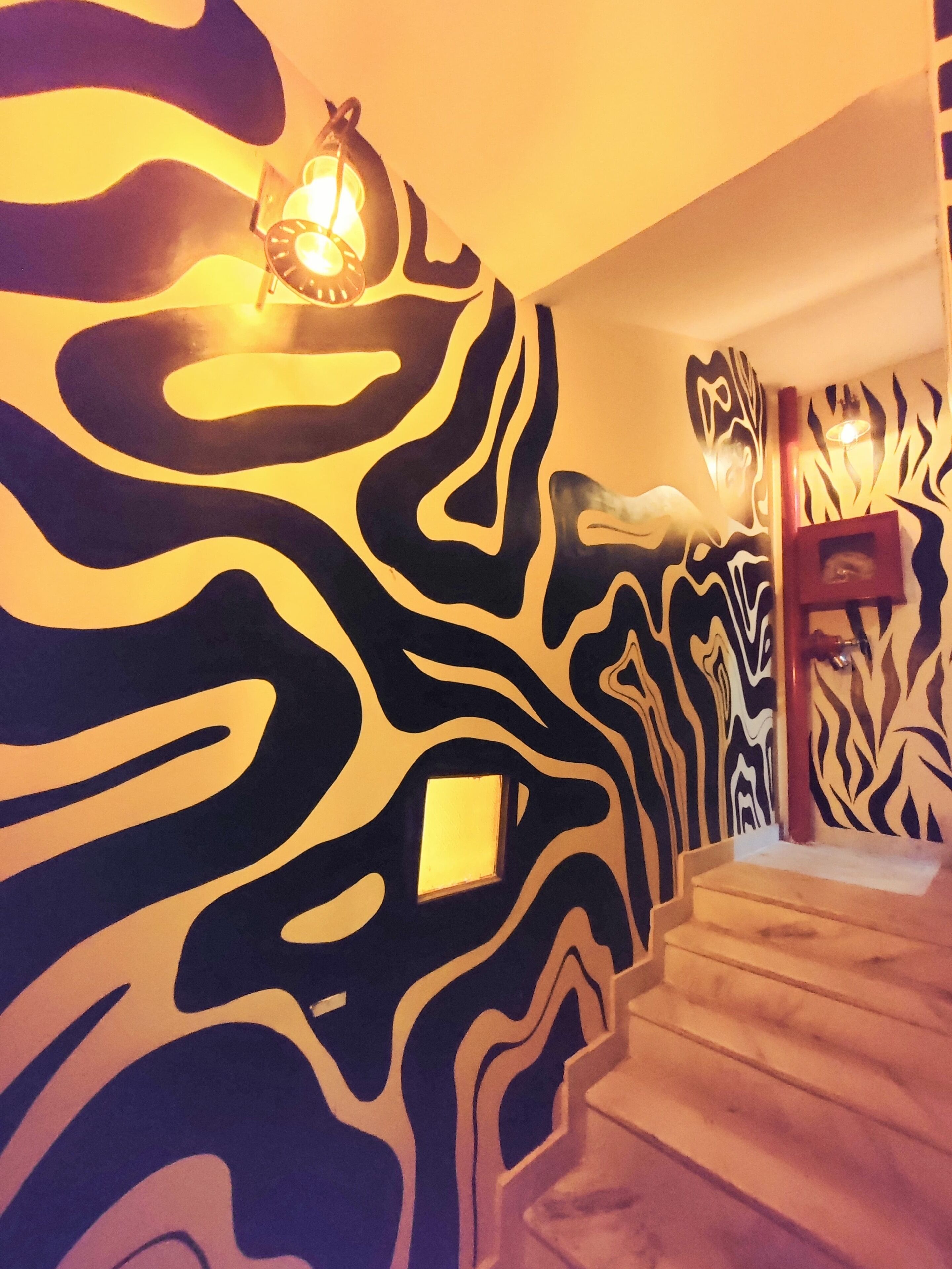 Un escalier avec un mur décoré de motifs zébrés et une petite fenêtre.