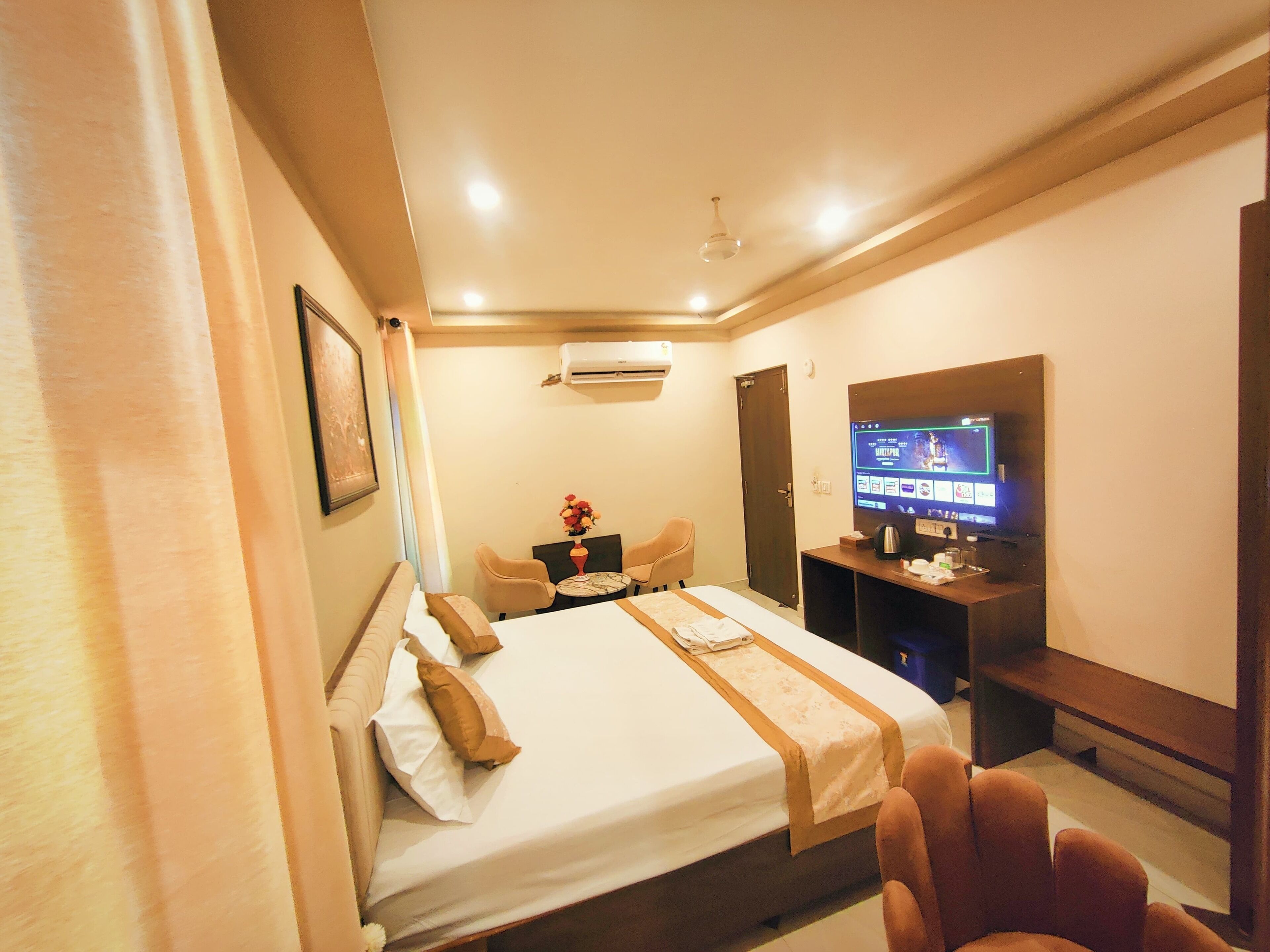 A hotel room with a bed, a desk with a computer, a TV, and a chair.