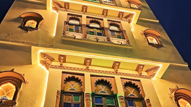 Un edificio de varios pisos con detalles arquitectónicos ornamentales y ventanas iluminadas.