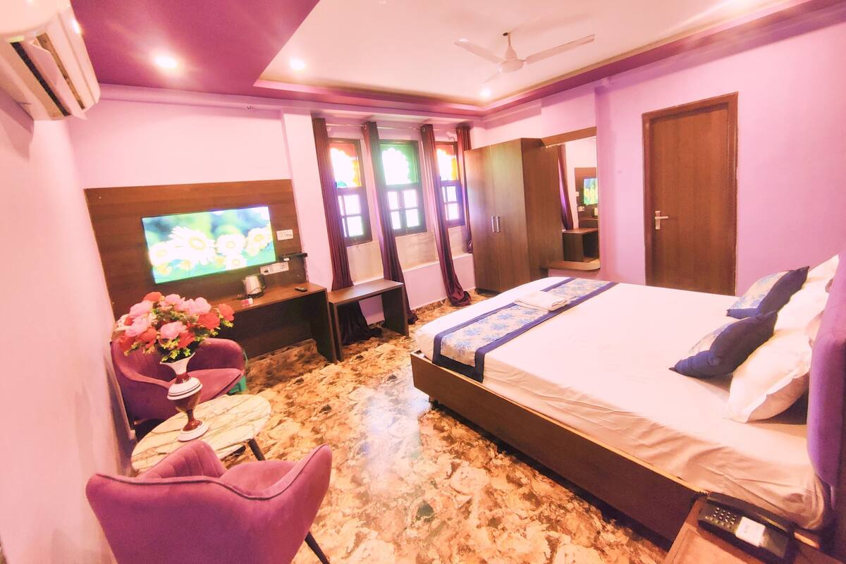 A hotel room with a bed, a TV, a desk, a chair, and a bathroom.