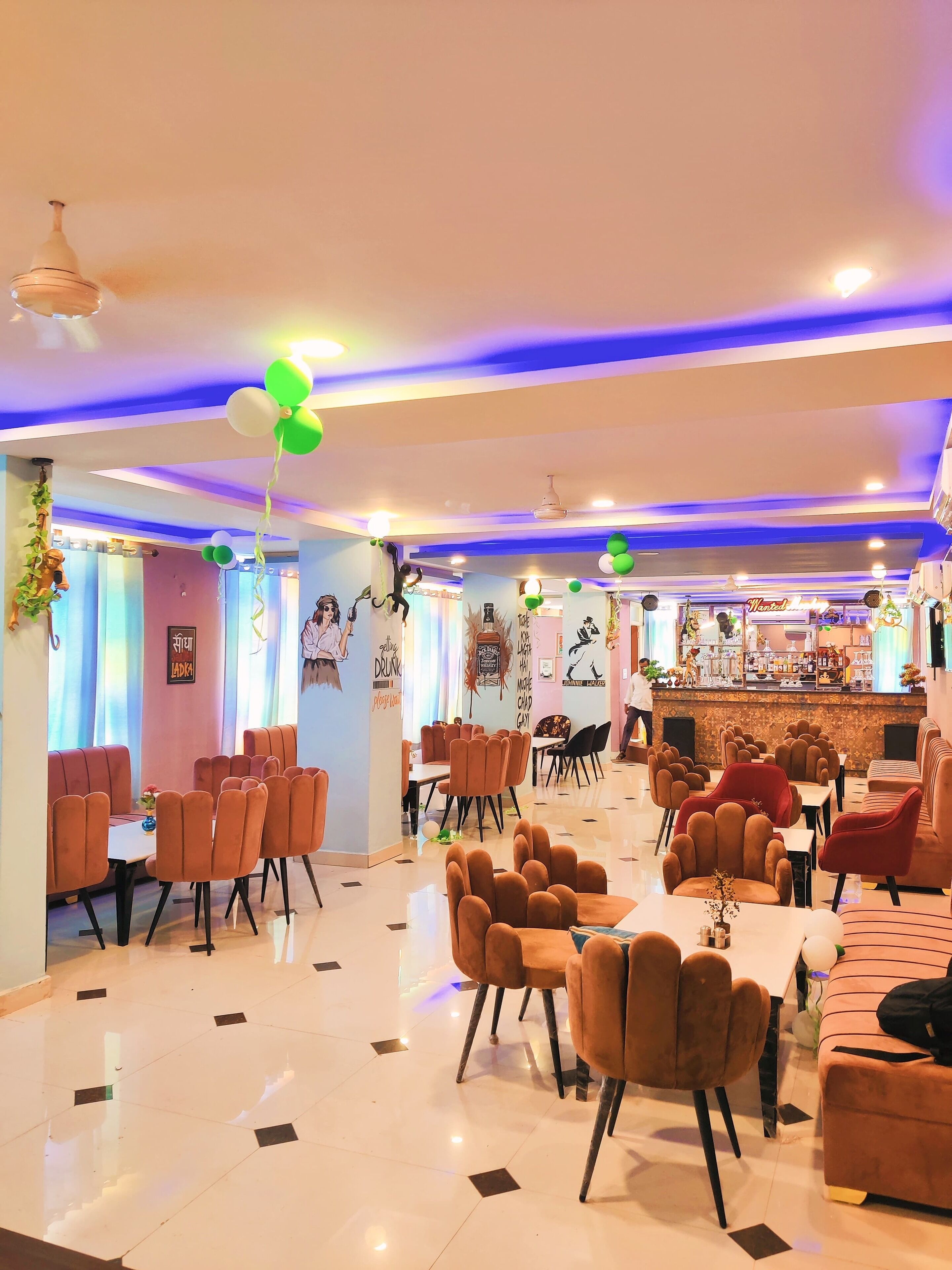 A spacious restaurant with multiple seating areas, including booths and tables, and a bar in the background.