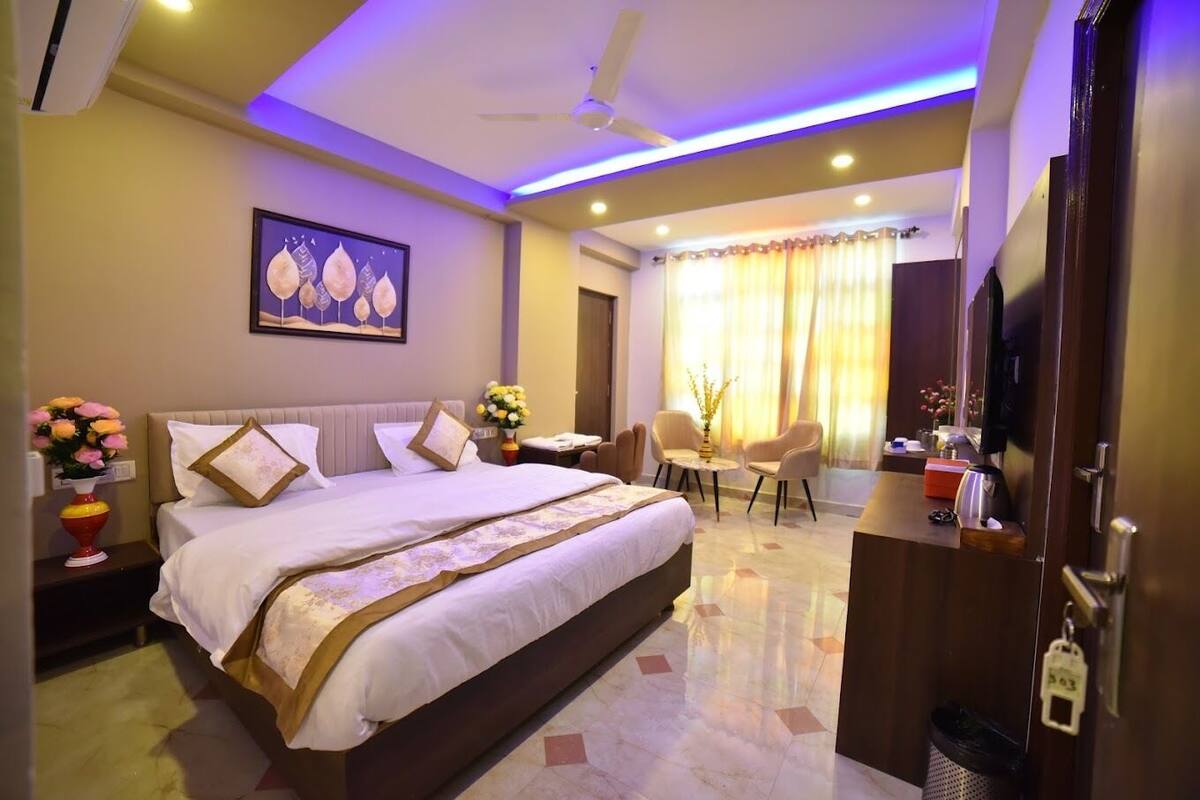 A hotel room with a large bed, a desk, a chair, a ceiling fan, and a painting on the wall.