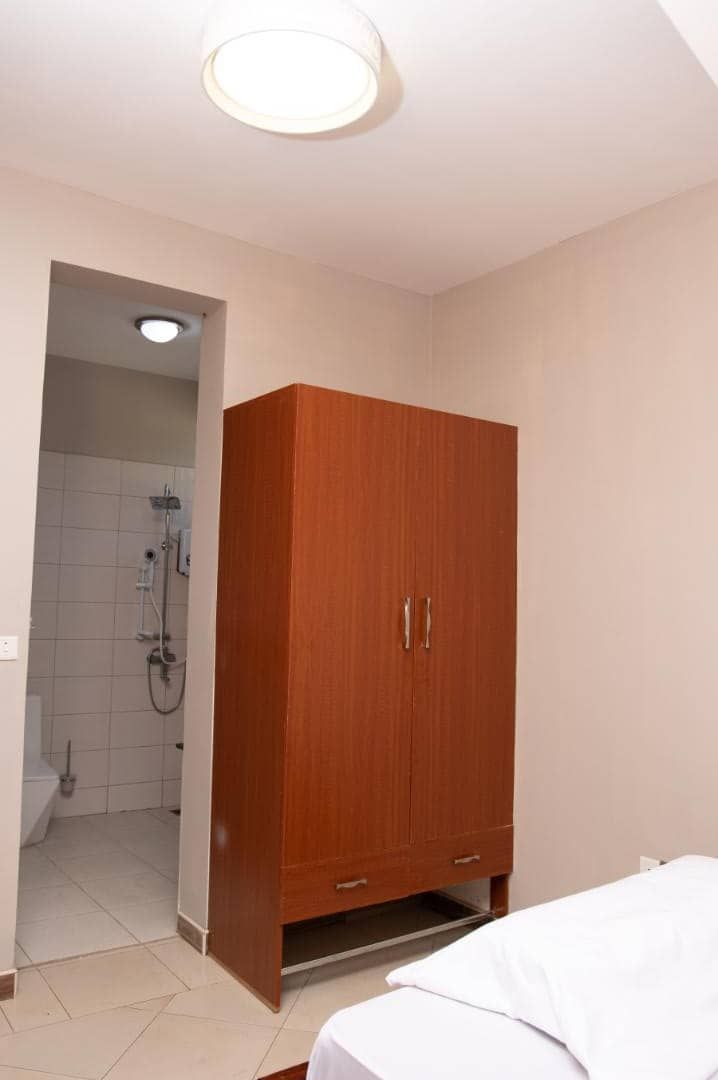 Une chambre avec une armoire en bois, un lit et une salle de bain avec douche.