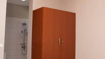 Une chambre avec une armoire en bois, un lit et une salle de bain avec douche.