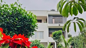 A modern two-story building with a well-maintained garden in front. - Simba Villa (Arusha)
