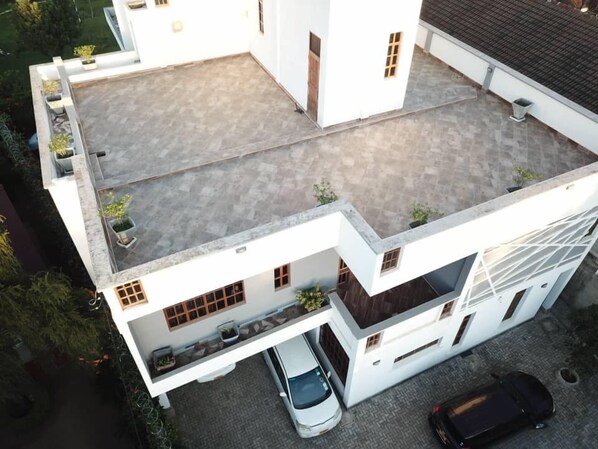 A modern two-story house with a flat roof, a covered patio, and a car parked in the driveway. - Simba Villa (Arusha)