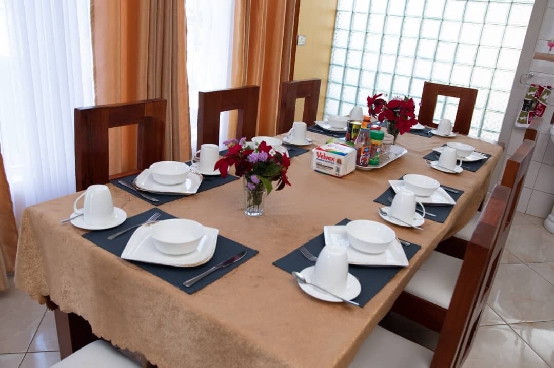 Taula de dinar preparada per a sis amb vaixelles blanques, un ram de flors i una caixa de Velveez.