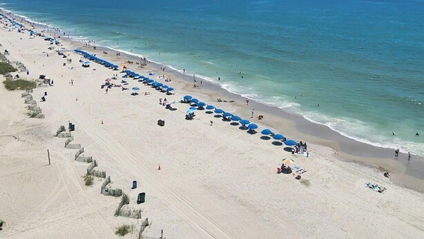 Een strand met een lange rij parasols en mensen.