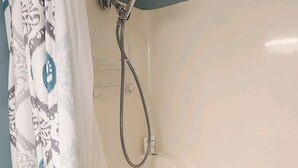 Een badkamer met een bad, douche en een gordijn met patroon.