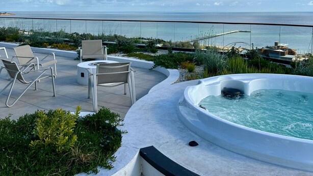 Une terrasse sur le toit avec un jacuzzi, un espace salon et une vue sur la mer.