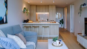 Une cuisine moderne dotée d’un îlot central, de tabourets de bar et d’un coin repas avec une table et des chaises blanches.