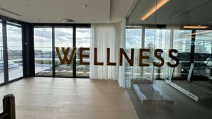 Une pièce spacieuse avec de grandes fenêtres, un plafond apparent et le mot « BIEN-ÊTRE » inscrit au centre.