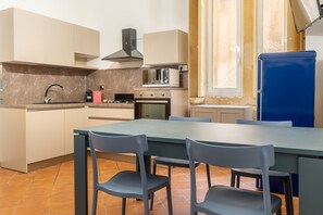 A modern kitchen with a dining area, featuring a gas stove, microwave, oven, and a blue refrigerator.
