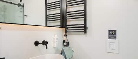 Un baño moderno con un lavamanos blanco, un perchero, un inodoro y un espejo.