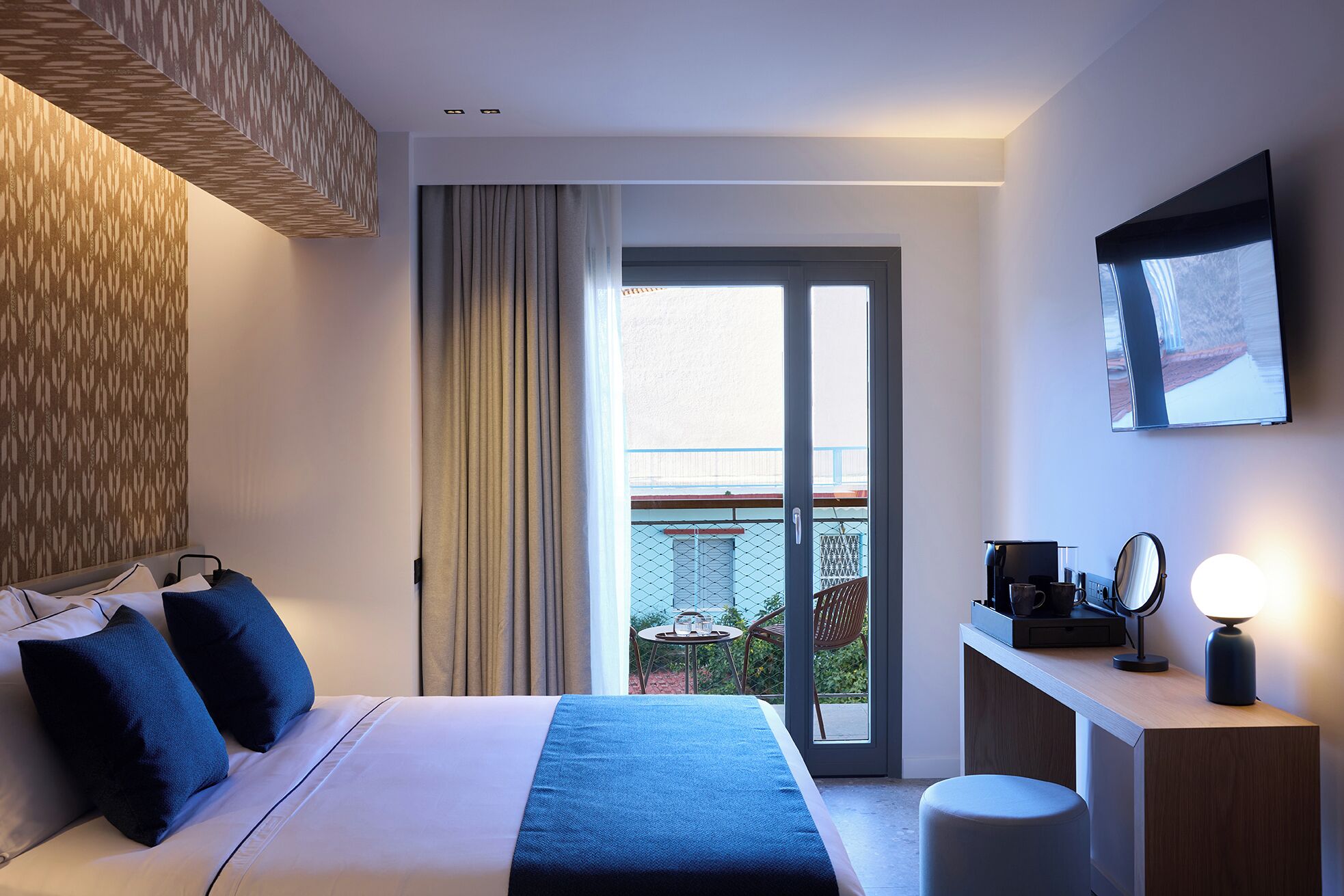 Una habitación de hotel moderna con una cama grande, un escritorio con espejo y vistas al exterior.