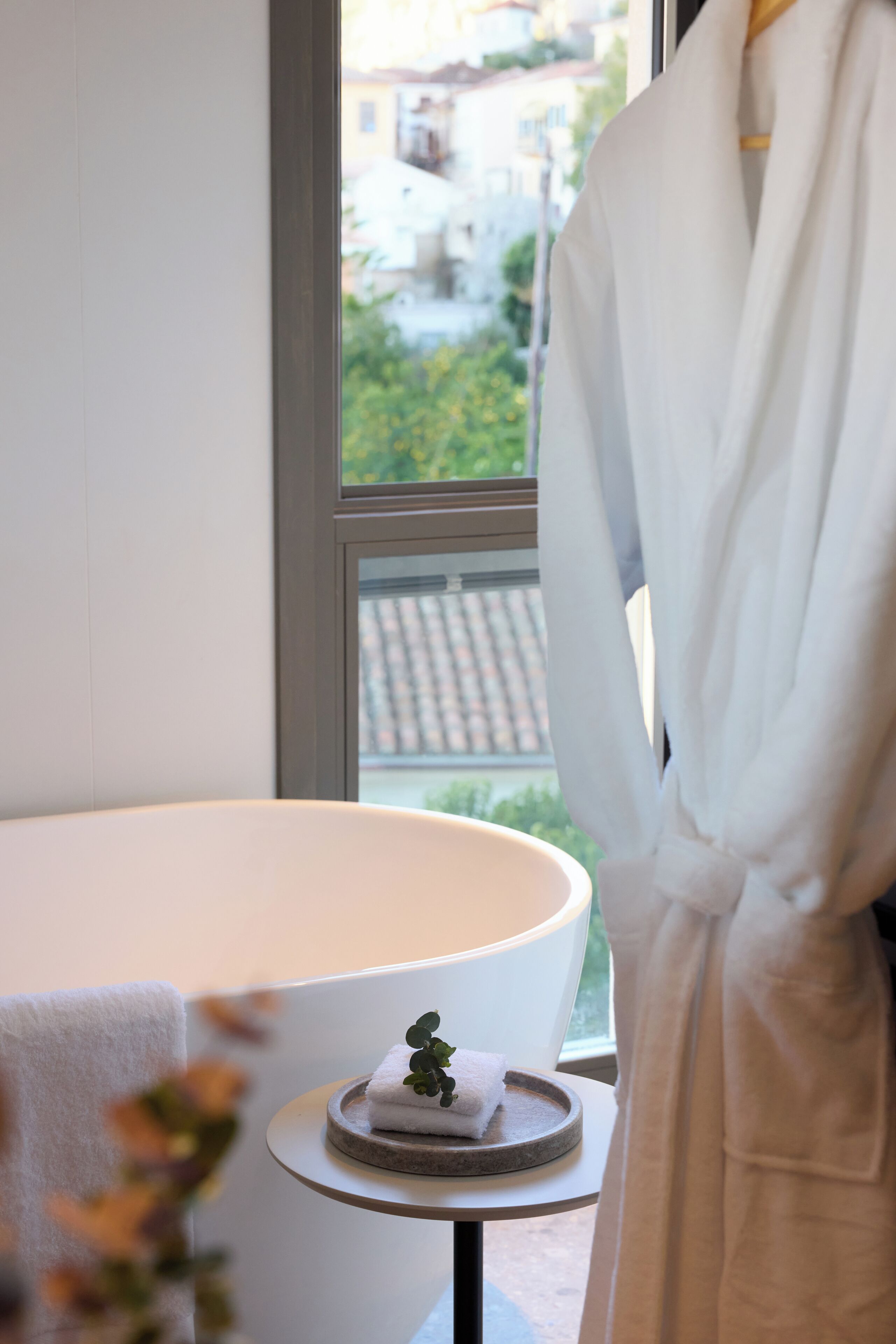 Un baño con una bañera, una toalla y una bata colgadas junto a la ventana.