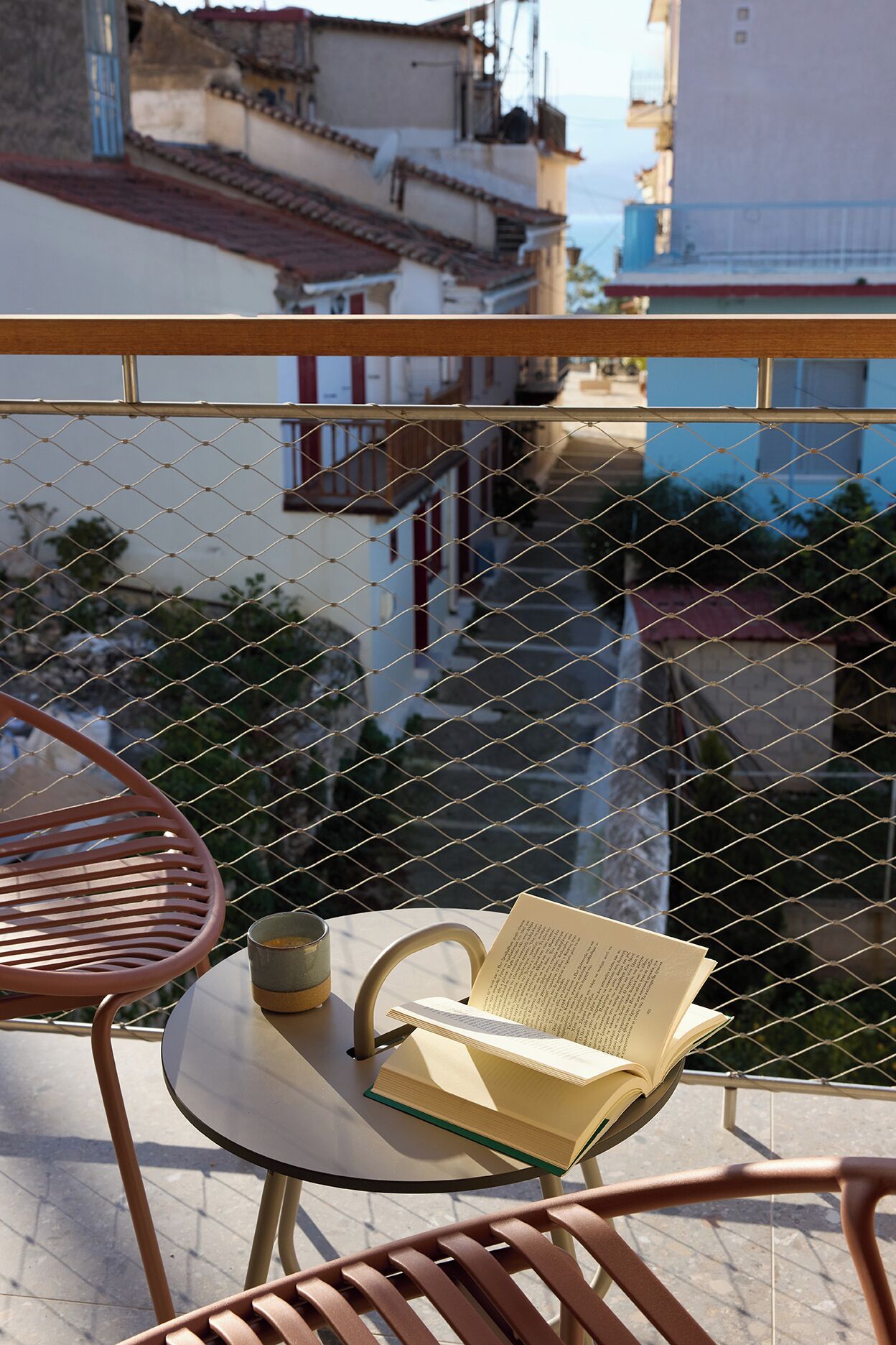 A balcony with a table, chairs, and a book.