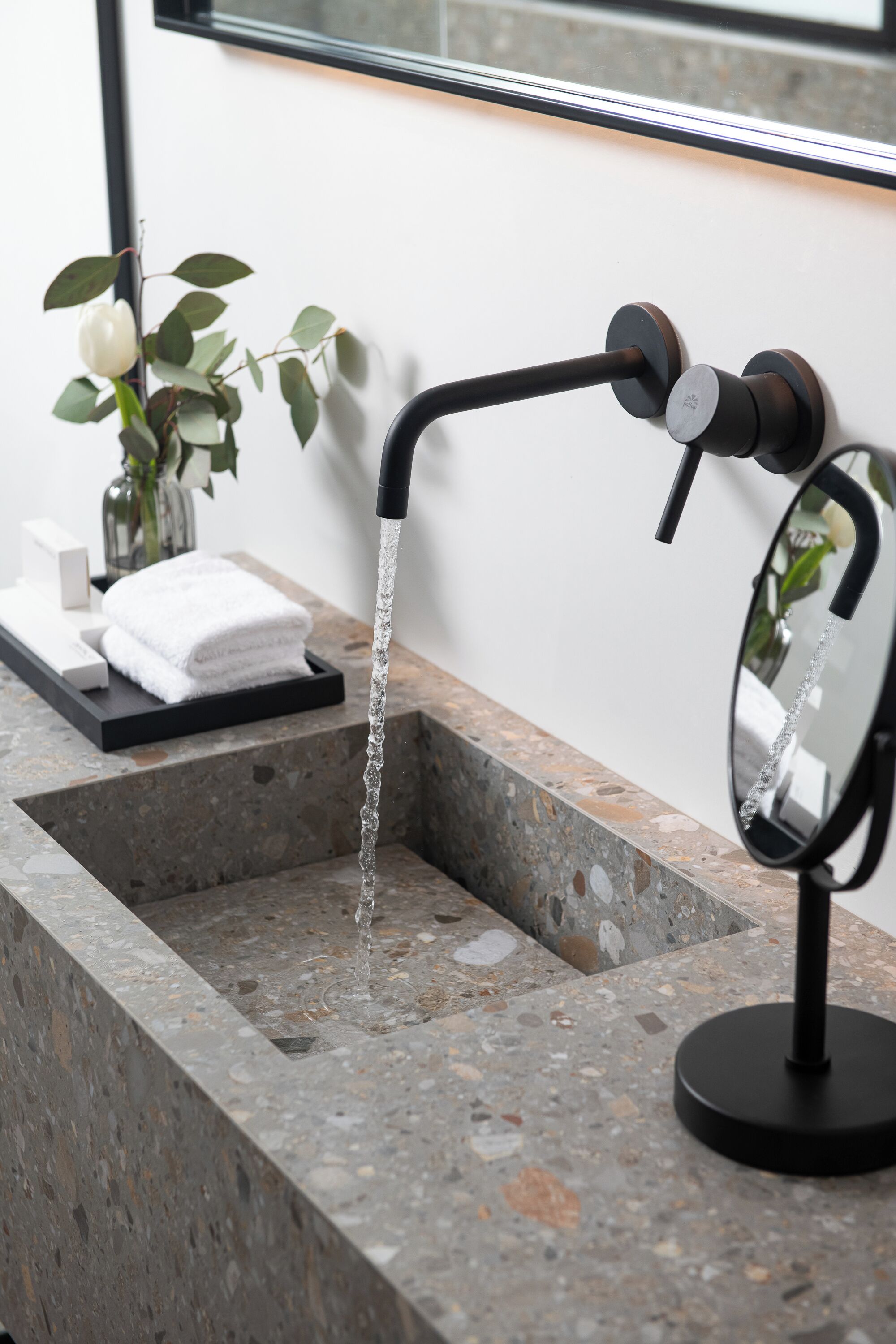 A bathroom with a granite countertop, a black faucet, and a mirror.